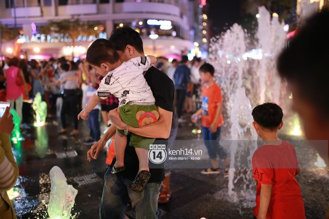 Sài Gòn tối mùng 1 Tết: Trẻ em thích thú cởi áo, nhảy vào đài phun nước đường hoa Nguyễn Huệ để nô đùa - Ảnh 12.