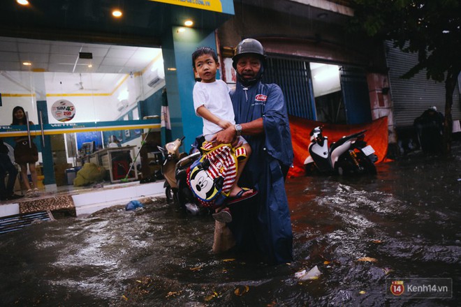 Phụ huynh ẵm bồng con nhỏ, bì bõm lội nước về nhà sau cơn mưa lớn ở Sài Gòn - Ảnh 7.