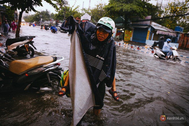 Phụ huynh ẵm bồng con nhỏ, bì bõm lội nước về nhà sau cơn mưa lớn ở Sài Gòn - Ảnh 6.