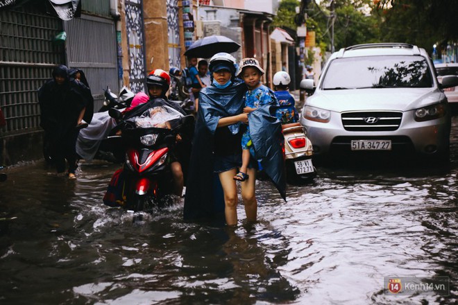 Phụ huynh ẵm bồng con nhỏ, bì bõm lội nước về nhà sau cơn mưa lớn ở Sài Gòn - Ảnh 14.
