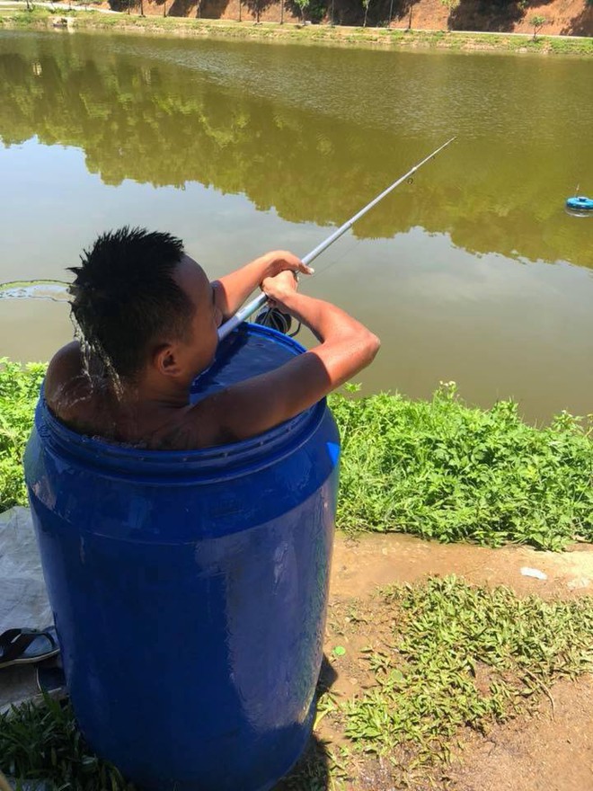 Thời tiết n&oacute;ng 40 độ, người đ&agrave;n &ocirc;ng ngồi trong th&ugrave;ng phuy c&acirc;u c&aacute; - ảnh 1