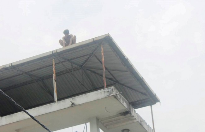 Giải cứu nam thanh ni&ecirc;n leo n&oacute;c nh&agrave;... chỉ tay l&ecirc;n trời la h&eacute;t - Ảnh 1.