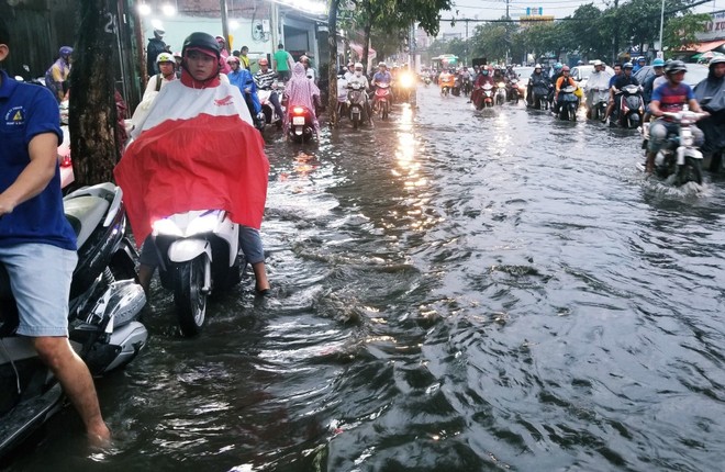 Người dân bì bõm lội nước đẩy xe về nhà vì nhiều tuyến đường ở Sài Gòn bị ngập nặng - Ảnh 1.