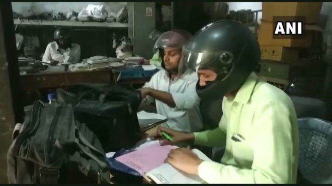 Đáng ngẫm hình ảnh công chức Ấn Độ đội mũ bảo hiểm trong phòng làm việc - Ảnh 1.