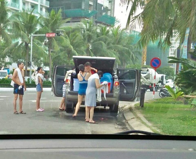 Góc bệ rạc: Đỗ xe bán tải giữa đường, cả gia đình thản nhiên đứng tắm - Ảnh 1.