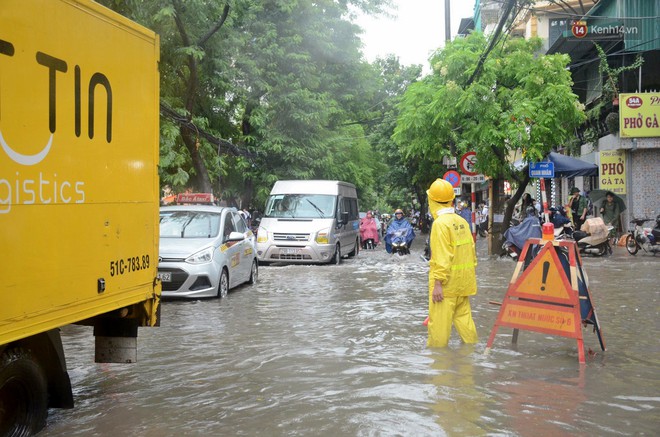 Người dân ngã sóng soài giữa dòng nước ngập trên đường phố Hà Nội sau cơn mưa - Ảnh 1.