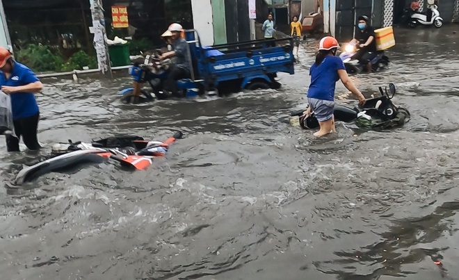 Người Sài Gòn bất lực đứng nhìn xe máy lật ngang, trôi bồng bềnh trên đường ngập nặng - Ảnh 1.