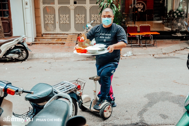 Quán phở diễn xiếc lạ nhất Hà Nội: Đội tô nước lèo nóng hổi thăng bằng trên đầu, chân lướt như bay bằng xe điện trong khu ngõ nhỏ để phục vụ khách - Ảnh 3.