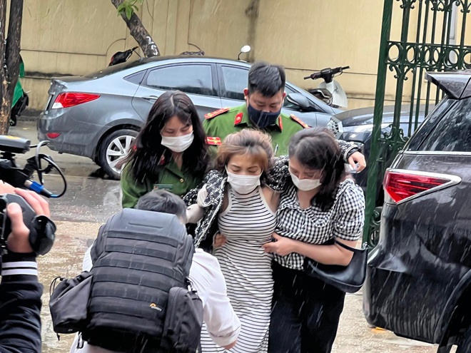 Ảnh: Nữ nghi phạm phóng hỏa gây cháy nhà trọ bị hạ đường huyết, đi không vững được dìu vào trụ sở lấy lời khai - Ảnh 1.