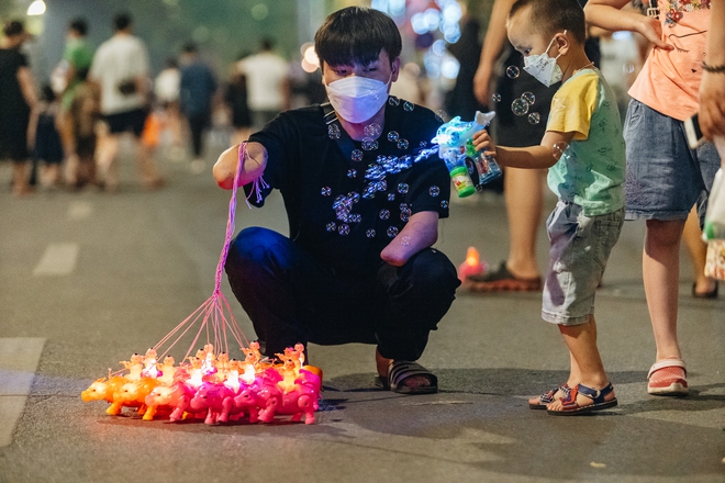 8 năm sau vụ nổ bình oxy, chàng trai cụt hai tay làm thiết kế, cuối tuần bán hàng rong ở phố đi bộ hồ Gươm để nuôi mẹ bệnh tật - Ảnh 1.