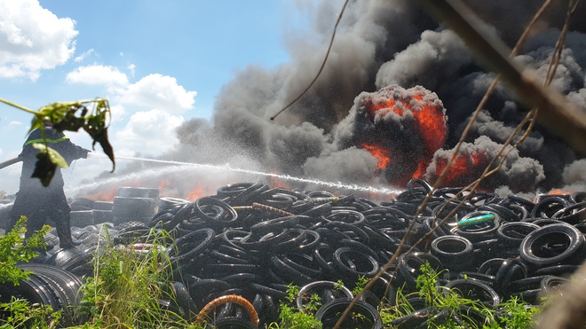 TP.HCM: Khói lửa cuồn cuộn tại bãi lốp xe, người dân phá tường cho cảnh sát vào chữa cháy - Ảnh 2.