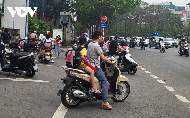 Nhiều phụ huynh H&agrave; Nội kh&ocirc;ng đội mũ bảo hiểm, lượn l&aacute;ch trong giờ tan tầm đi đ&oacute;n con - Ảnh 3.