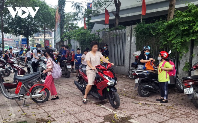 Nhiều phụ huynh H&agrave; Nội kh&ocirc;ng đội mũ bảo hiểm, lượn l&aacute;ch trong giờ tan tầm đi đ&oacute;n con - Ảnh 1.