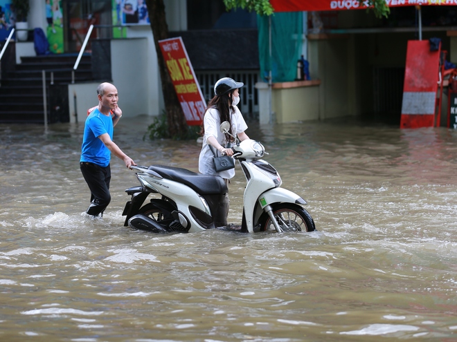 Trời hửng nắng, nhiều tuyến đường ở Hà Nội vẫn ngập sâu, người dân dùng tấm chắn để ngăn nước tràn vào nhà- Ảnh 16.