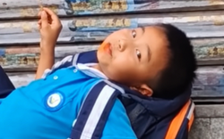 Mẹ đến đón muộn, cậu bé thản nhiên nằm trên bậc thềm ăn đồ ăn: Dân mạng bật cười vì quá chill!