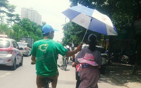 Hình ảnh dễ thương ngày Hà Nội nóng đỉnh điểm: Người đàn ông chạy xe đạp che ô cho hai mẹ con trên phố