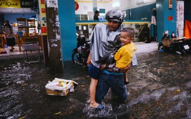 Phụ huynh ẵm bồng con nhỏ, bì bõm lội nước về nhà sau cơn mưa lớn ở Sài Gòn