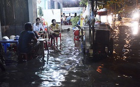 Người dân bì bõm ngồi ăn uống ngay trên đỉnh triều cường ngập ở Sài Gòn