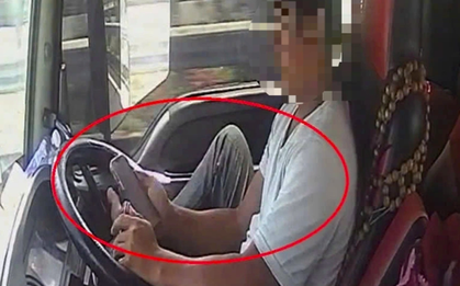 Tài xế dùng chân điều khiển xe đầu kéo chạy trên cao tốc, tay cầm điện thoại lướt TikTok