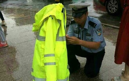 Hình ảnh cảnh sát trẻ dầm mưa nhường áo bảo hộ cho em bé đi lạc khiến hàng triệu trái tim tan chảy
