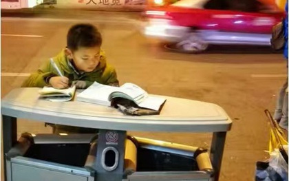 Hình ảnh cậu bé chăm chỉ học bài trên thùng rác cạnh xe khoai lang nướng của mẹ gây xúc động mạnh