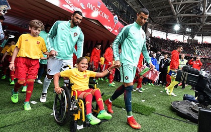 Ronaldo như một người cha, ân cần đẩy xe lăn cho cô bé mascot khuyết tật