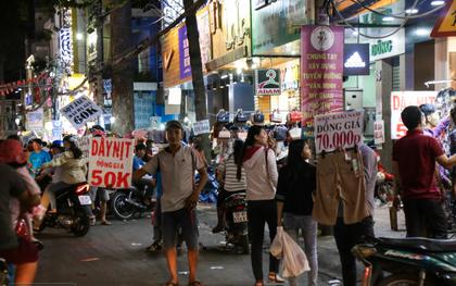 Nhiều nhân viên cửa hàng thời trang ở Sài Gòn cầm bảng giá tràn ra đường chào mời khách dịp cận Tết