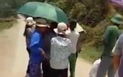 Người dân ngồi che ô chờ xe chở lợn đi qua để xin tiền