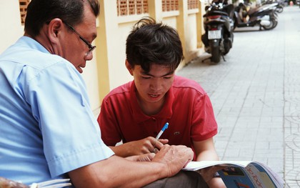 "Lớp học" đáng yêu trên vỉa hè: Một bác bảo vệ vừa giữ xe vừa dạy chữ cho cậu nhóc bán hàng rong ở Sài Gòn