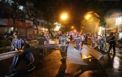 Ảnh: Cảnh sát PCCC&CNCH Hà Nội đội mưa để dọn tấm tôn lớn bay xuống đường