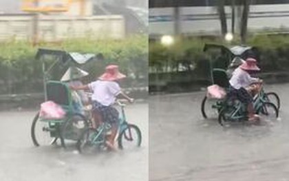 Xúc động em nhỏ còng lưng đạp xe, đẩy xe người khuyết tật khi mưa to, đường ngập