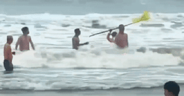 Nhân viên bảo vệ cầm cờ lao xuống biển ngăn du khách tắm lúc sóng to gió lớn gây xôn xao