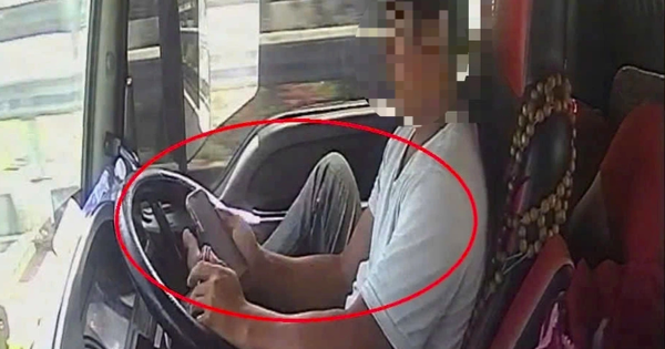 Tài xế dùng chân điều khiển xe đầu kéo chạy trên cao tốc, tay cầm điện thoại lướt TikTok