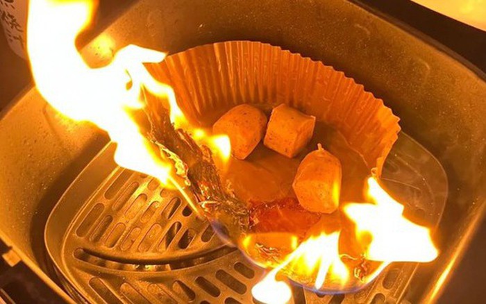 Air fryer liner visibly burning, illustrating the potential fire hazard from loose paper in an air fryer